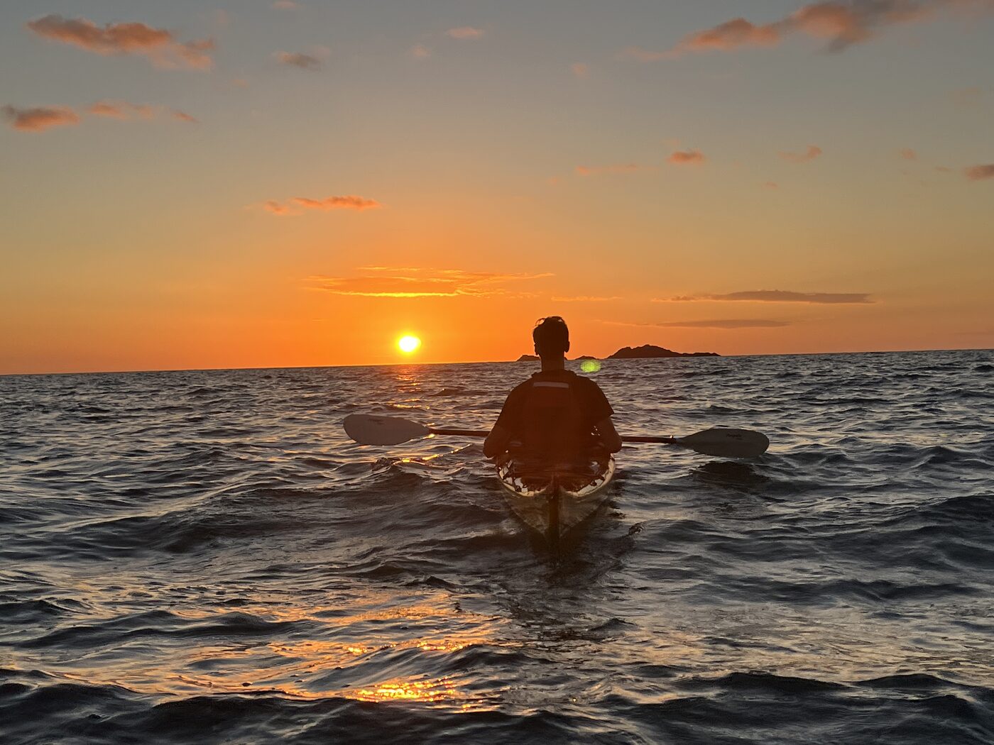 Erik Kraayenhof kayaking into the sunset, paddle in hand